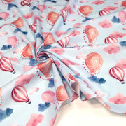 Tissu cotonnade enfant aux montgolfières roses et nuages sur fond bleu ciel - tissuspipi.com